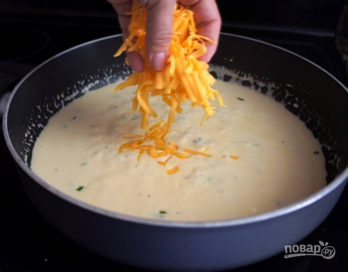 Сыр натрите на крупной терке и всыпьте на сковороду к остальным ингредиентам. Протомите несколько минут, пока сыр полностью не расплавится.