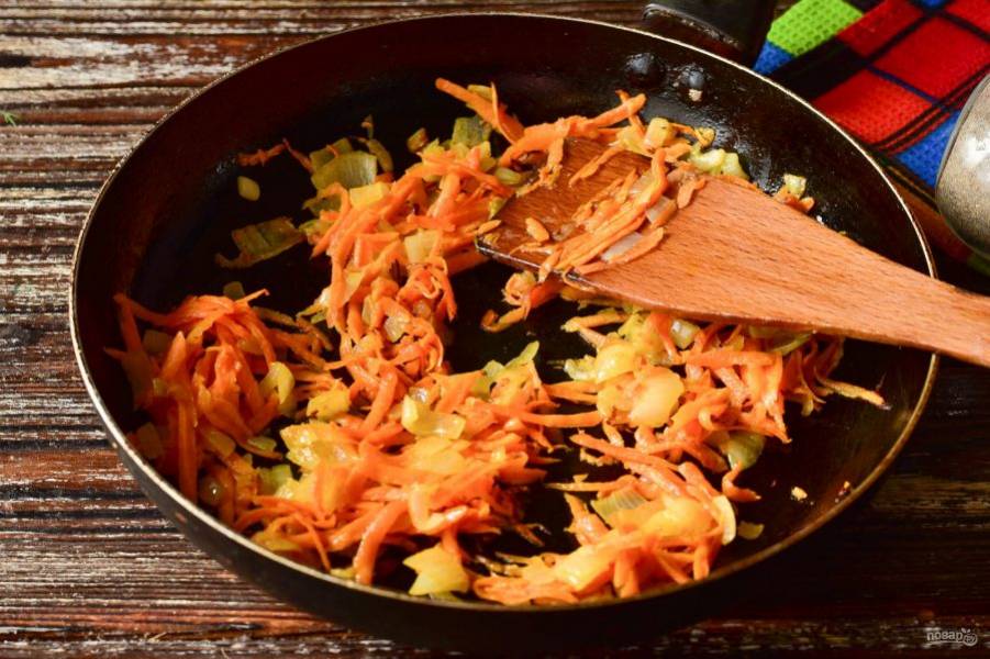 В сковороде разогрейте растительное масло. Выложите нерезаный лук и натертую на терке морковь. Обжарьте овощи в течение 2-3 минут.