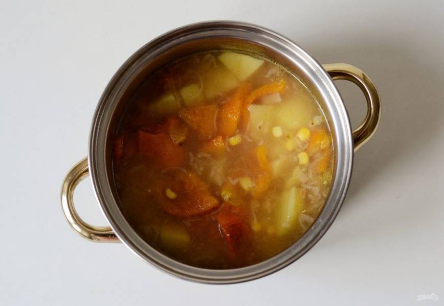 Добавьте печеный перец, чеснок и кукурузу. Варите суп еще 5-7 минут.