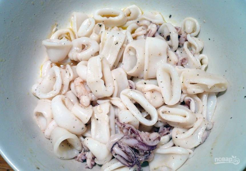 Затем переложите морепродукты в миску, добавьте растительное масло, соль и перец. Все перемешайте и оставьте кальмаров мариноваться на пару часов в холодильнике.