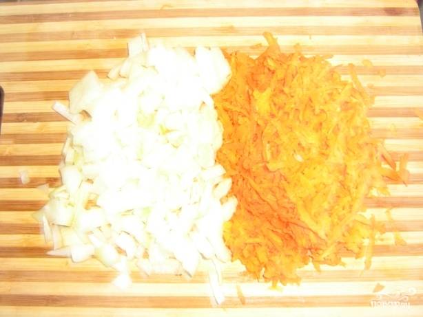 Лук мелко нарезаем, а морковь трем на терке. Обжариваем овощи на сковороде с добавлением масла.