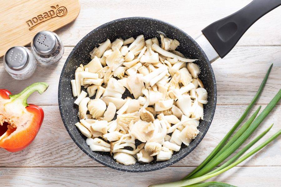 Грибы вешенки помойте, нарежьте на крупные кусочки. Разогрейте сковороду на среднем огне и выложите грибы. Обжарьте их на огне чуть выше среднего до легкого румяного цвета, пока не выпарится лишняя жидкость.