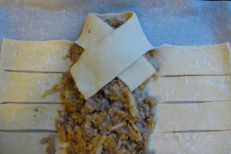 2. Теперь аккуратно заворачиваем надрезанные края, чтобы получалась "косичка". Смажьте руки маслом, чтобы к ним не прилипало тесто.