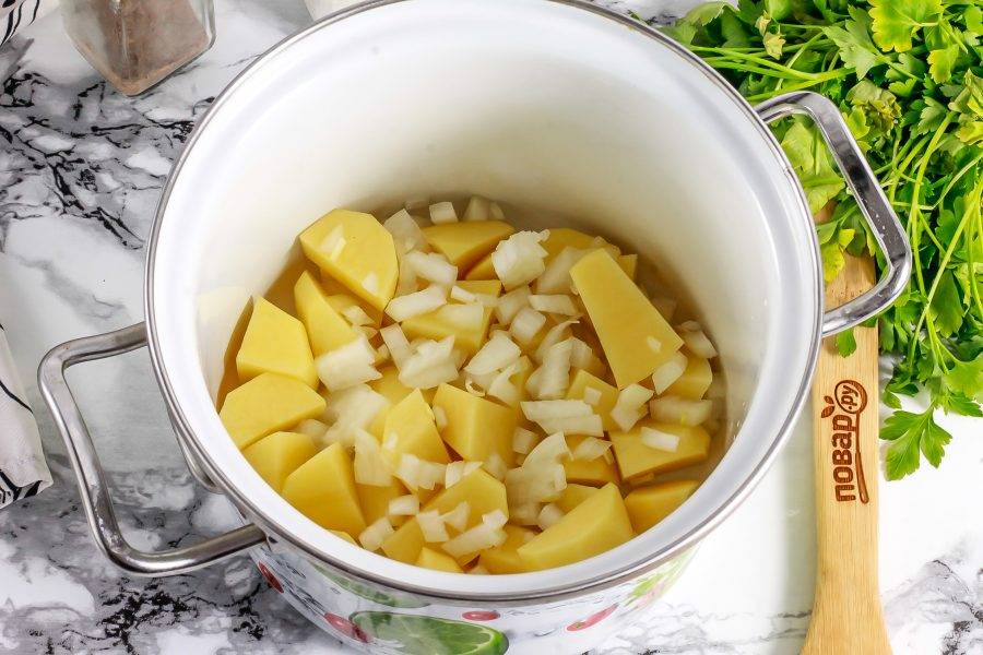 Картофель, лук и морковь очистите от кожуры и промойте в воде. Нарежьте картофель средними кубиками, а лук — мелкими и высыпьте в кастрюлю, в которой собираетесь варить суп.