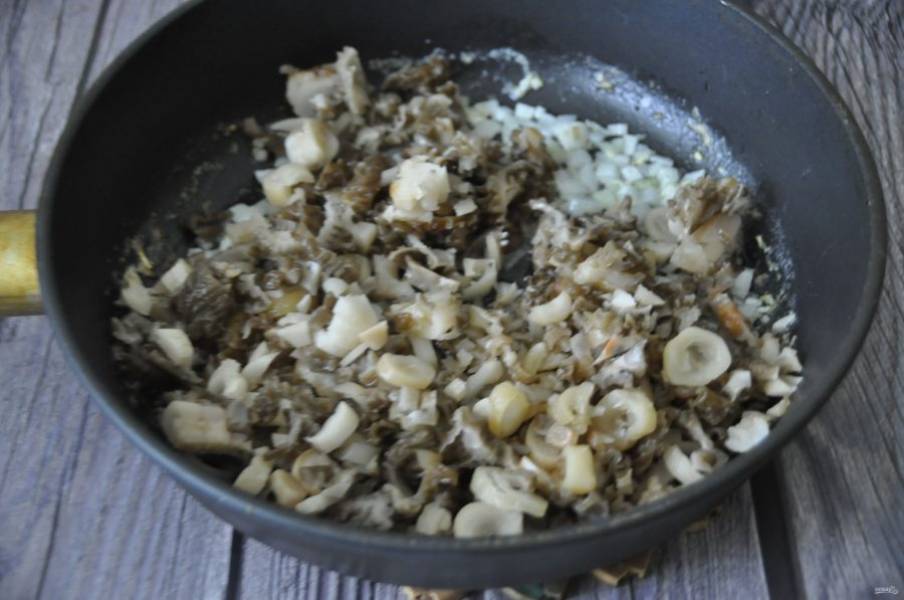 На разогретую сковороду выложите масло, обжарьте лук до золотистого цвета, добавьте к луку мелко нарезанные грибы, жарьте пока не испарится влага.