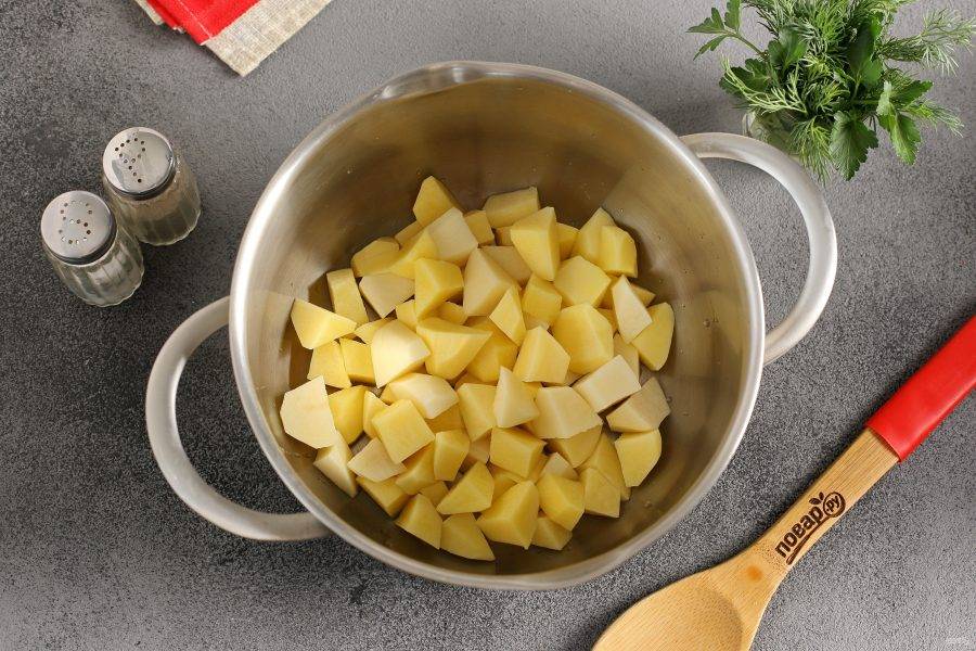 Картофель нарежьте кубиками и переложите в кастрюлю.
