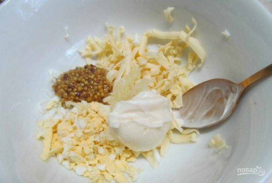 В миску натрите сыр. Смешайте его с горчицей, майонезом, отваренным заранее яйцом и измельчённым чесноком.
