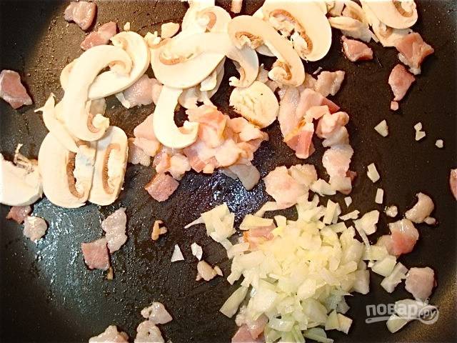 5.	Через 1 минуту выложите к бекону грибы и луковицу, перемешайте и обжаривайте до румяного цвета.