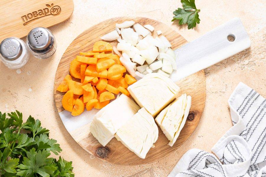 Морковь помойте, очистите и нарежьте кружочками. Репчатый лук нарежьте крупными ломтиками. Капусту разрежьте на кусочки среднего размера.