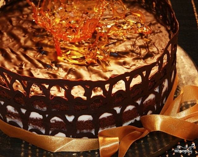 Из 110 грамм сахара сварите карамель для украшения. Дайте торту на застывание примерно 2 часа, после чего уберите пергаментную бумагу. Украсьте карамелью — и можно подавать.