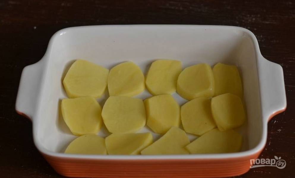 Картофель очистите от кожуры. Вымойте его и нарежьте на пластинки. Затем смажьте форму для запекания растительным маслом и выложите в нее слой кружочков картофеля. 