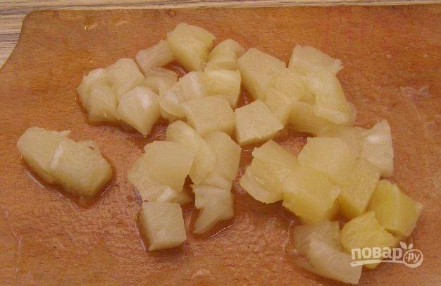 Для этого рецепта вам понадобятся консервированные ананасы. Откройте банку, слейте из нее лишнюю жидкость. Достаньте ананасы, порежьте их на небольшие кусочки. 