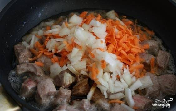 4. Обжарьте свинину. К ней в сковородку выложите морковку и лук. Когда овощи пустят сок, добавьте молотый перец и влейте соевый соус. Долейте воду. Тушите под крышкой до готовности. В зависимости от жесткости мясо будет готово в течение 15-30 минут.