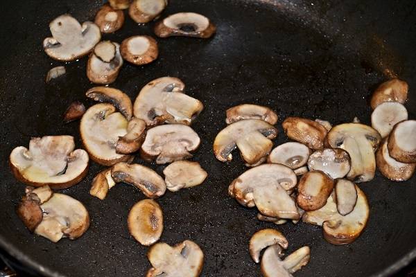 1. Первым делом необходимо вымыть, слегка обсушить и нарезать грибы. На сковороде разогреть растительное масло и отправить туда грибы. Обжарить их до готовности, посолив и поперчив по вкусу. 