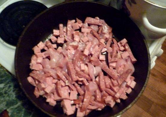 Разогреваем в сковороде немного масла и обжариваем на нем до румяной корочки нарезанную куриную грудку, вареную и копченую колбаску.