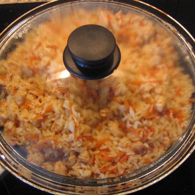 Отваренный рис добавить к курице с морковью и тщательно перемешать. Накрыть крышкой и дать настояться 5 минут, затем огонь выключить.
