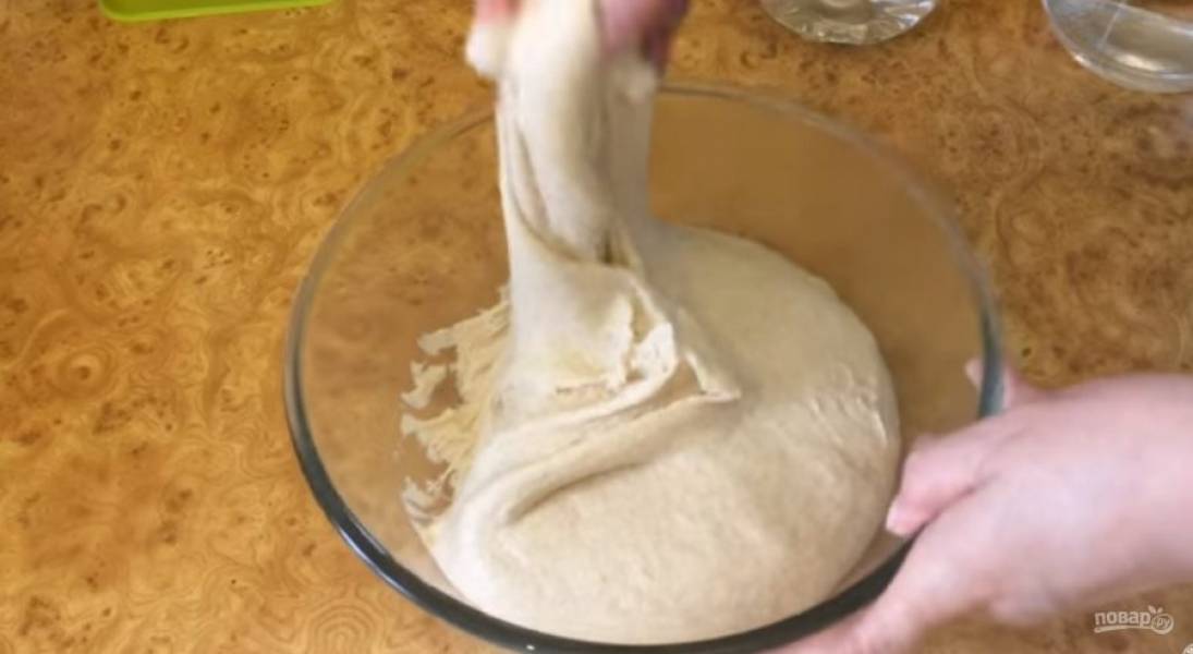 4. Через полтора часа обомните тесто: возьмите один край теста, максимально растяните его и сложите к противоположной стороне миски, и так — по кругу. Переверните тесто на другую сторону и выровняйте его поверхность смазанными маслом руками.