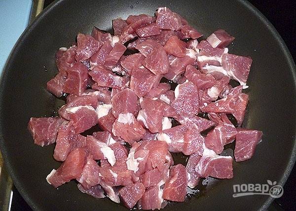 На сковороду с маслом выложите небольшие кусочки свинины. Добавьте немного горячей воды. Тушите мясо с маслом в течение 35 минут под крышкой.