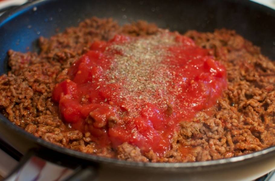 Добавляем измельченные помидоры в собственном соку (если их нет, можно добавить простой кетчуп или томатный соус) и специи. Перемешиваем и готовим еще 4-5 минут, после чего снимаем с огня и подаем с отваренными до готовности спагетти. При подаче можно посыпать тертым сыром и свежей зеленью.