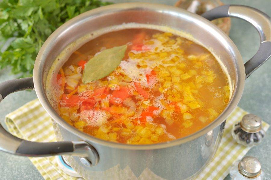 Помидор мелко нарежьте, переложите в кастрюлю, сразу добавьте лавровый лист. Если любите в постных супах вкус и аромат чеснока — самое время его добавить. Варите суп 5 минут.