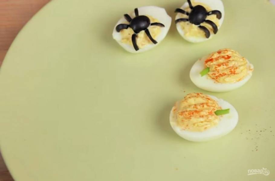 3. Из второго яйца также выньте желток, смешайте его с майонезом, горчицей и кетчупом и поместите обратно в яйцо. Затем зубочисткой сделайте углубления (такие, как на поверхности тыквы). Из зеленого лука вырежьте корешок тыквы. 