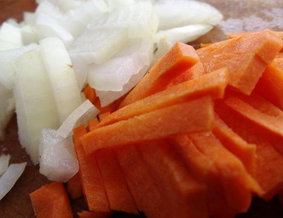 Пока мясо варится, порежьте и обжарьте на сковороде луки и морковь. В конце жарки добавьте томатную пасту и отправьте к мясу в бульон.