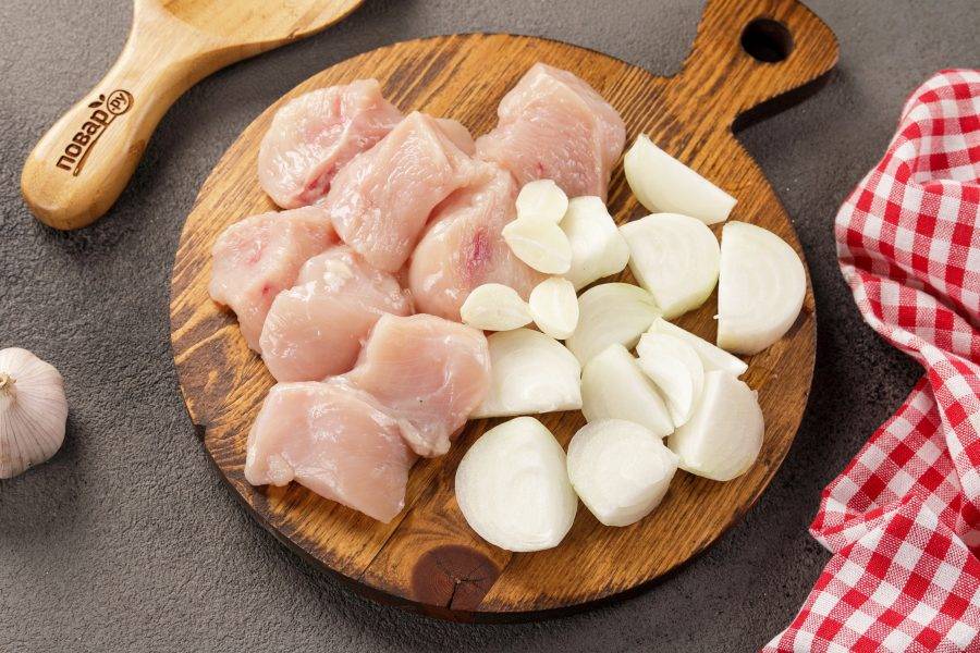 Тем временем филе промойте и обсушите, нарежьте кусочками. Лук и чеснок очистите и разрежьте на несколько частей.