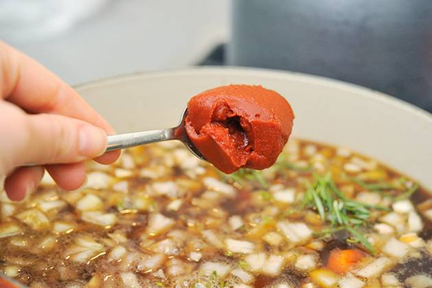 Влейте оставшийся бульон, добавьте томатную пасту и специи.
