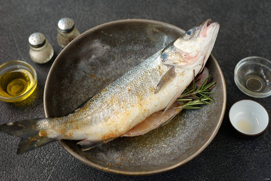 Натрите рыбу снаружи и внутри маслом, специями и приправами, вложите в брюшко розмарин. 