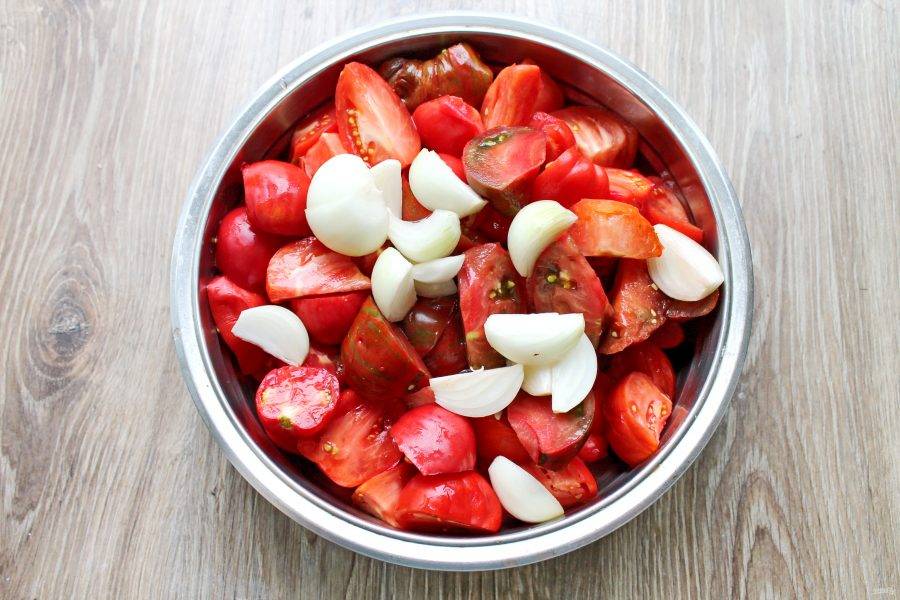 Репчатый лук почистите, сполосните и порежьте на дольки, добавьте к порезанным помидорам.