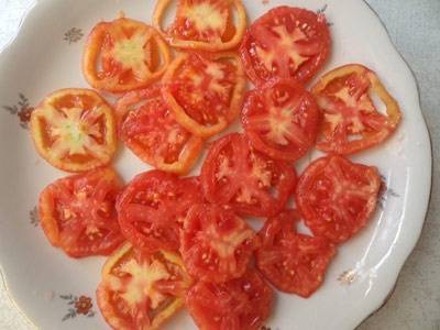 Вырезаем место крепления плодоножки, затем нарезаем помидоры кружочками как можно тоньше. Выкладываем их на блюдо и поливаем столовой ложкой оливкового масла. 