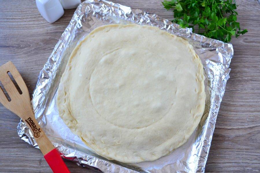 Накройте пирог сверху вторым пластом теста. С помощью подходящей по диаметру тарелки сделайте легкое углубление.