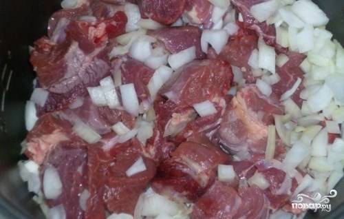 Мясо промойте, зачистите от жира и жилок. Нарежьте на крупные куски. Очистите и помойте лук. Также порежьте его крупно. Сложите лук и мясо в чашу мультиварки. 