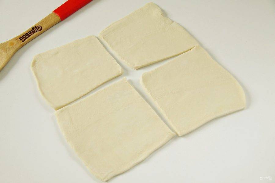 Слоеное тесто раскатайте на присыпанной мукой поверхности и разделите на четыре части.
