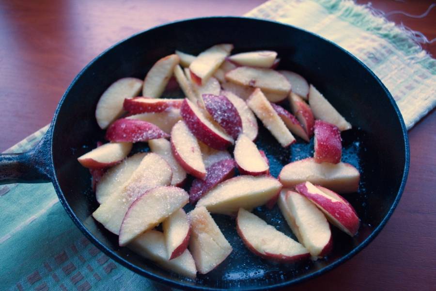 На отдельной сковороде растопите сливочное масло. Добавьте яблоки и сахар. Карамелизируйте яблоки 3-5 минут.