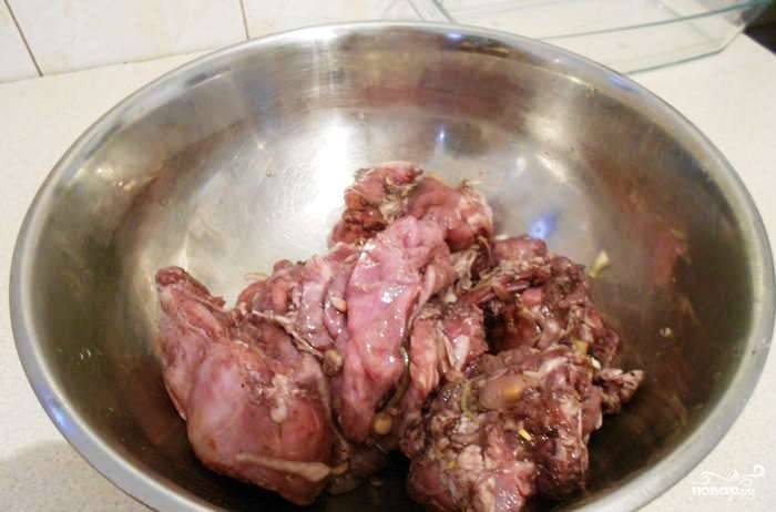 Выньте мясо из холодильника, слейте из миски вино. Отберите куски кроля от колец лука и чернослива. 