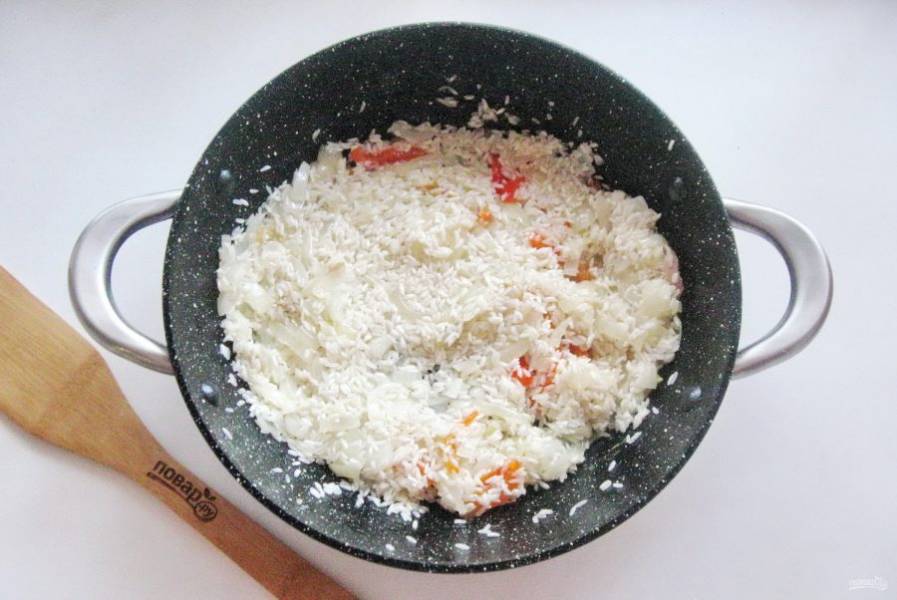 Рис помойте и добавьте к овощам в сковороду. Жарьте рис с овощами 3-4 минуты перемешивая.