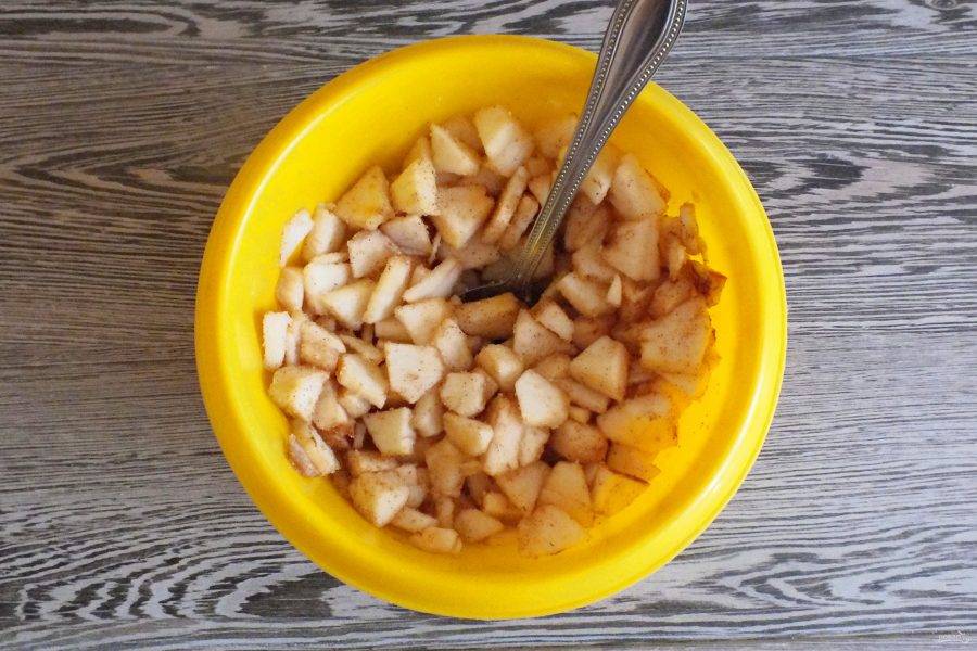 Сделайте яблочную начинку. Яблоки очистите от кожуры и удалите семенную коробочку. Нарежьте на небольшие, тонкие кусочки. Переложите в чашу, добавьте сахар и корицу. Перемешайте, отставьте на время приготовления теста.