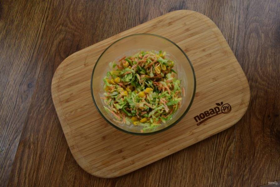 Добавьте консервированную кукурузу. Перемешайте все в миске.  Чеснок измельчите и соедините с майонезом. Заправьте салат.