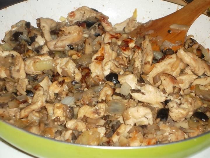 Добавьте к курице грибы, маслины и лук. Готовьте еще 5-7 минут.