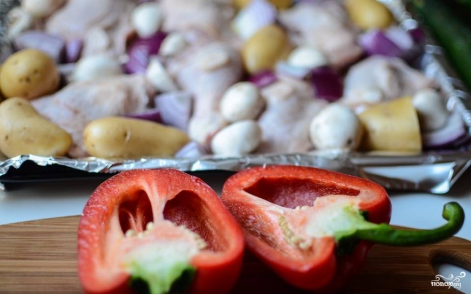 Добавьте к курице и картофелю грибы. Смажьте всё оливковым маслом. Разрежьте болгарский перец и вычистите его от семян. Порежьте на маленькие кусочки.