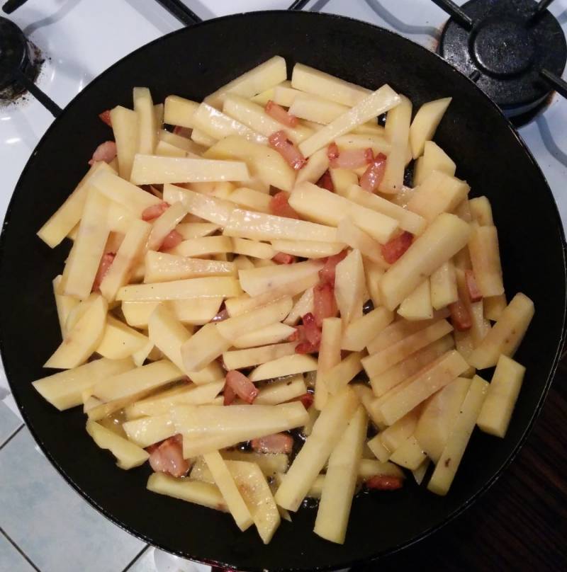 Добавляем картошку, перемешиваем и жарим 3-5 минут. После чего солим, перчим и жарим еще 13-15 минут до полной готовности картошки.