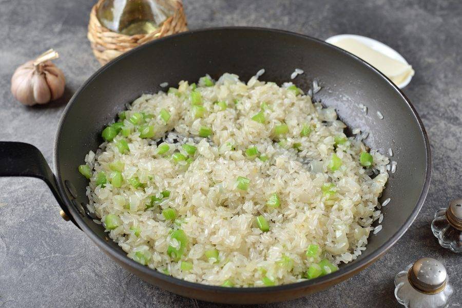 Всыпьте в сковороду рис, перемешайте и обжарьте его около минуты с овощами. Кстати, рис для ризотто не промывают. 