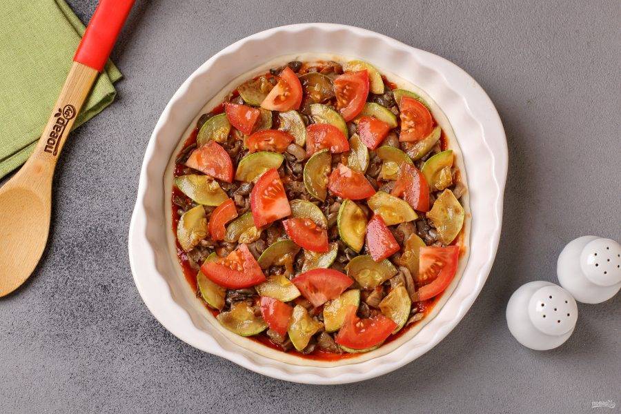 Смажьте тесто любимым соусом и выложите сверху начинку: обжаренные кабачки, обжаренные грибы с луком и нарезанные дольками помидоры.