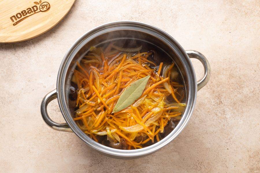 Следом добавьте овощную зажарку, лавровый лист. Посолите и поперчите суп. Варите на небольшом огне до мягкости картофеля.