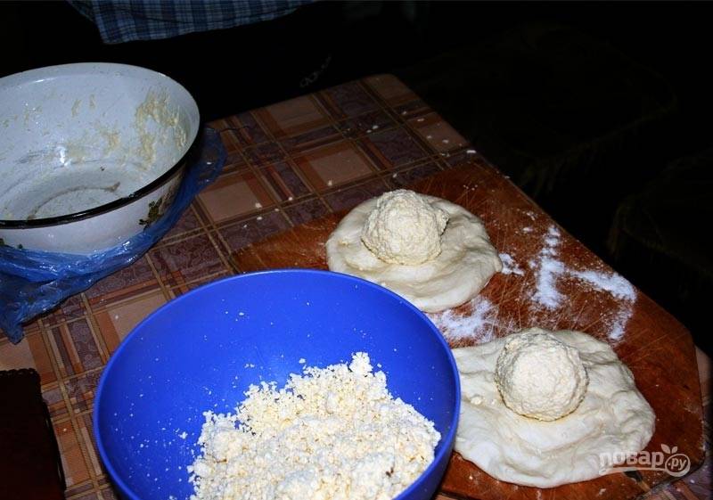 Тесто раскатайте в лепёшки шириной в 4 см. В центр каждой положите шарик сыра.
