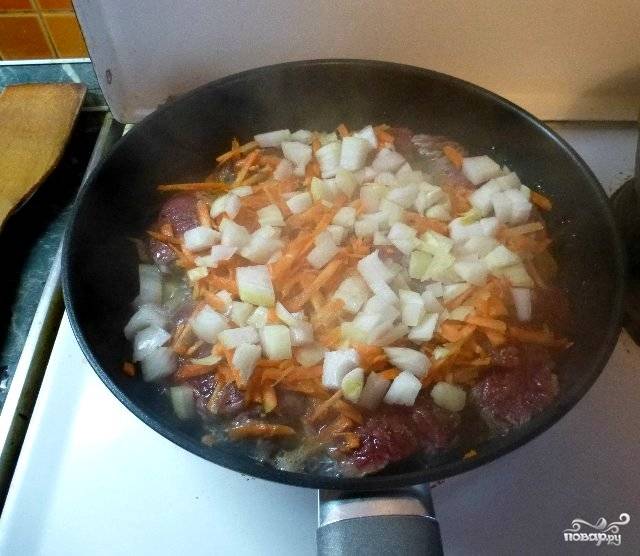 Морковь трем на крупной терке, лек нарезаем небольшими кубиками. Выкладываем овощи в сковороду к свинине и продолжаем жарить все вместе. 