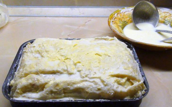Повторно выкладываем сырную начинку, масло и кефирную смесь. Накрываем последним листом лаваша (края заправит внутрь). Поливаем остатками масла и кефира с яйцами.