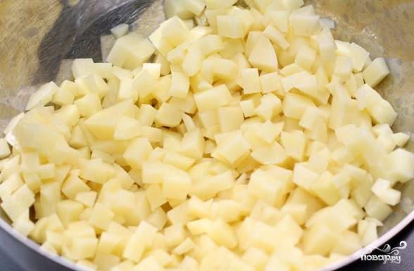 2. Подготовьте начинку. Для этого почистите картофель. Нарежьте на маленькие кусочки. Очистите и мелко нарежьте лук. Мытую зелень порежьте. Все соедините в одной тарелке, посолите.