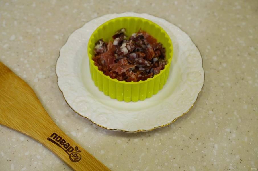 2. На тарелку поставьте формовочное кольцо и выложите первым слоем колбасу, затем немного майонеза.